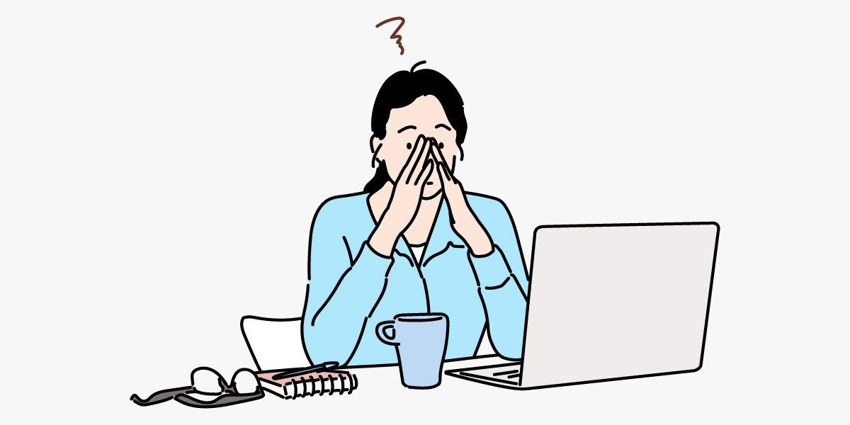 Tired, stressed young woman with eyes closed massaging her nose at her desk.